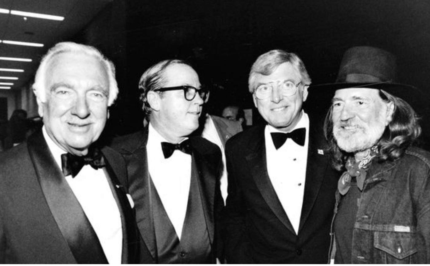 Mark White in black tie with Walter Cronkite, another guest, and Willie Nelson at a formal event.